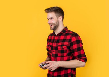 Dijital dünyada yaşamak. Erkek hobisi ve boş zaman. Kareli tişörtlü bir oyuncu. Mutlu sakallı adam oyun konsolu kullanıyor. joystick 'li traşsız yakışıklı adam. bilgisayar ve çevrimiçi oyun oyna