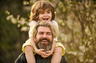 Başarıyı kutluyoruz. Parkta çiçek açan ağaç. çocukluk ve ebeveynlik mutluluğu. Sevgi ve destek. Baba ve oğul çiçek açan ağaçta. Bahar zamanı birlikte. Küçük çocuk babasıyla mutlu. Aile eğleniyor.