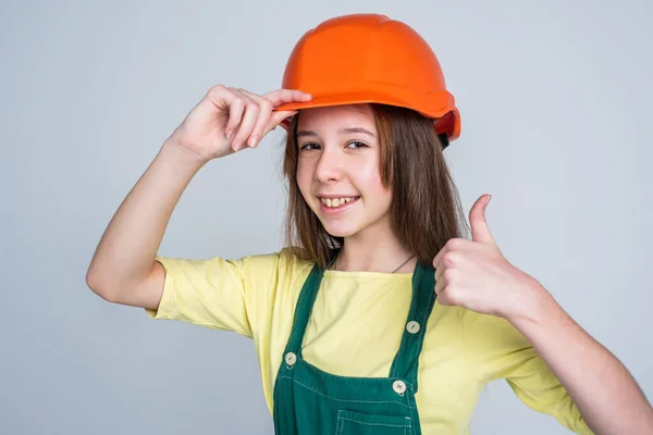 Menina adolescente alegre em uniforme de trabalho e capacete mostrar polegar para cima, engenheiro — Fotografia de Stock