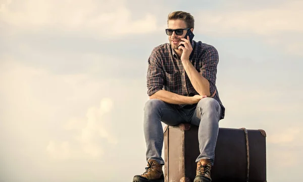 Sich zum Reisen verpflichten. Geschäftsmann mit Brille. Geschäftsreise. Macho Man Tourist Relax Tour Tasche. Männermode. sieht so trendy aus. sexy Mann Himmel Hintergrund sprechen am Telefon. Reisende warten auf Taxi. Umzug — Stockfoto