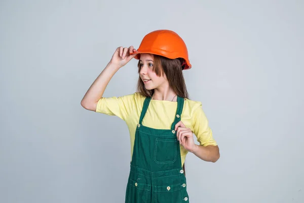 Lány gyermek visel egyenruhát és sisakot, miközben dolgozik a műhelyben, siker — Stock Fotó
