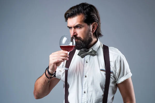 elegant brutal man in formal wear has groomed hair drinking wine, sommellier