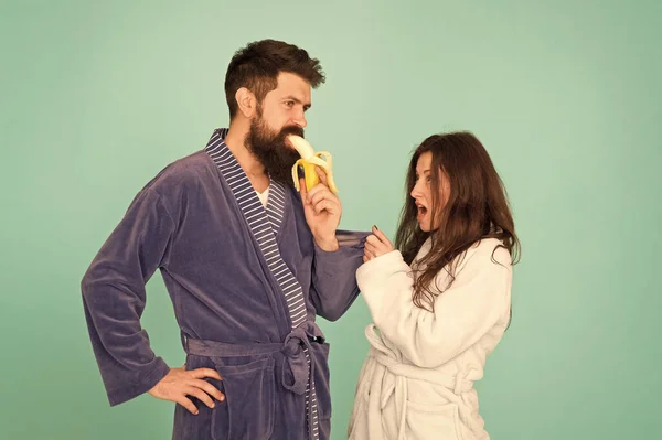 Sweet banana. Seductive hipster eat banana infront of woman. Using seduction tactics in family life. Scene of seduction. Couple in love blue background. Process of seduction. Seduction concept — Stock Photo, Image