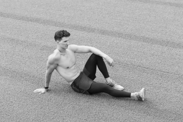 筋肉の男は草の上に座ることができます。トレーニングの後に静かにスポーツマンが休んでいる。草の上に座ってる男。リラックスして。スポーティライフスタイルのコンセプト。リラックスしたセクシートップレス男座っています上の草 — ストック写真