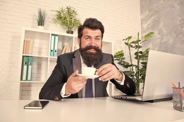 Diskutujte o obchodu s kávou. Muž pohledný šéf sedí v kanceláři a pije kávu. Pohodlný pracovní prostor. Vousatý obchodník formální oblek relaxující s kávou. Kancelářské životní návyky. Opravdu dobré cappuccino — Stock fotografie