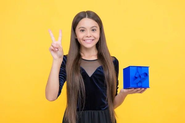 Glad flicka barn med långt hår grepp presentförpackning på gul bakgrund, köp — Stockfoto