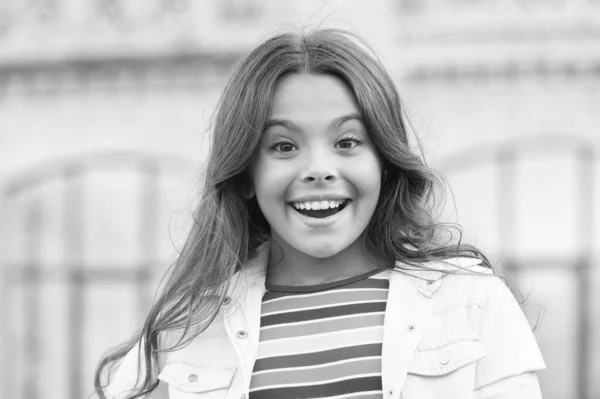 Pequeña chica hermosa peinado adorable sonrisa fondo urbano, alegre concepto de día — Foto de Stock