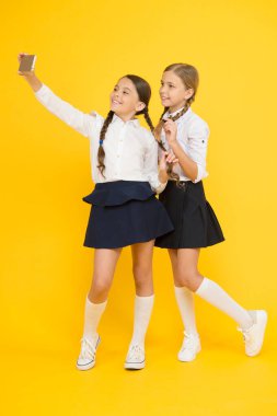 Birliktelik. Online eğitim. Bilgi günü. Akıllı telefonlu mutlu arkadaşlar. Çocuklar selfie çekerler, arkadaşlık yaparlar. Okul üniformalı küçük kızlar. Okula dönüyorum. Eğitim blogu. dijital teknoloji