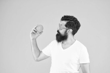 Diyet yapmanın tadını çıkar. Sarı arka planda turuncu renkli beslenme uzmanı. Sakallı adam narenciye ile besleniyor. Diyet günü için sağlıklı yiyecekler