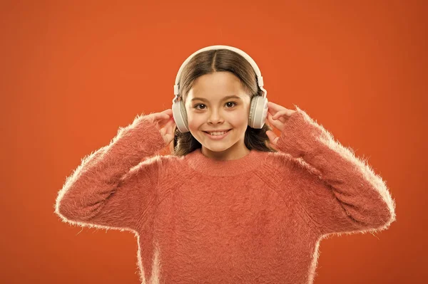 Kulaklıkla kulağına doğru ses iletiyor. Kablosuz kulaklıkla müzik dinleyen küçük bir çocuk. Modern kulaklık takan küçük bir kız. Tatlı çocuk kulaklıkla müzik sesinden hoşlanıyor. — Stok fotoğraf