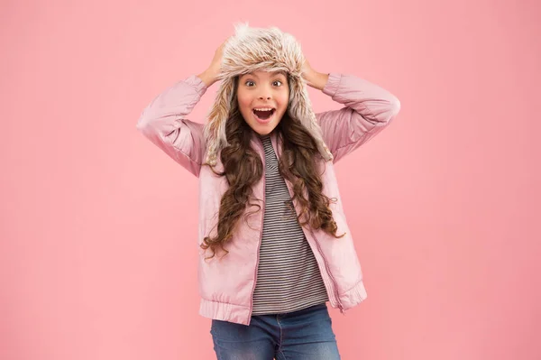 Jag kan inte tro på det. päls öronlapp hatt tillbehör. liten flicka vinter hatt. varma kläder för kalla årstider. Grabbmode. Hon ser ut som en hipster. Glad unge rosa bakgrund. höst stil. Barndomsverksamhet — Stockfoto