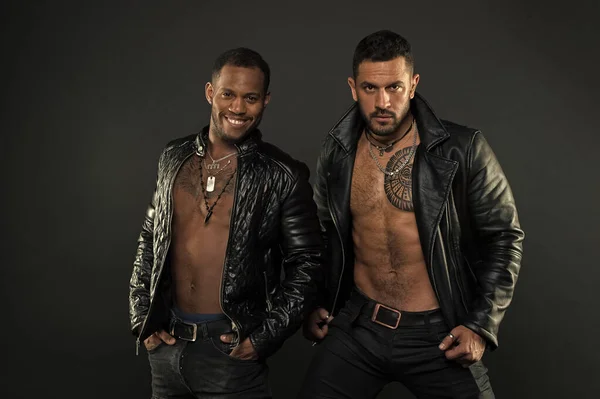 Biker mit sexy nackten Oberkörpern, rebellisches Konzept. Brutale Männer in Lederjacken vor schwarzem Hintergrund. Models in trendigen Männeraccessoires. Afrikanische und hispanische Männer mit tätowierter Brust — Stockfoto