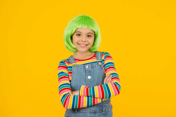 Schönheitswahn. Schönheitslook des kleinen Modells. Glückliche Mädchen tragen grüne Haare Perücke gelben Hintergrund. Mode und Schönheit. Schönheitssalon — Stockfoto