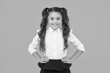 Merhaba okul. Sarı arka planda gülümseyen küçük okul çocuğu. Resmi giyinmiş, uzun esmer saçlı sevimli küçük bir çocuk. Masum gülüşü olan şirin bir çocuk. Mutlu küçük kız okula geri dönüyor.