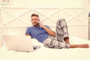 Uzaktan çalışma konsepti. Sosyal ağlar. Çevrimiçi dünya. İnternette sörf yapan adam. Çalışıyorum zaten. Dijital pazarlama. Uzaktan erişim. Hipster sakallı adam pijamalı serbest çalışan evde dinleniyor.