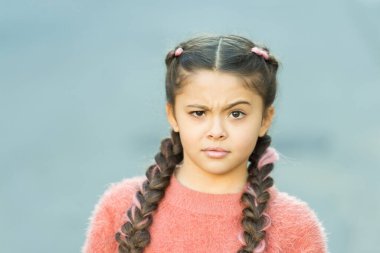 Yanlış olan ne? Şaşkın bakışlı küçük bir çocuk. Küçük çocuk uzun esmer örgüler takıyor. Sıradan moda tarzında sevimli bir çocuk. Dışarıdaki sevimli kız çocuğu. Çocukluk. Uluslararası Çocuk Günü