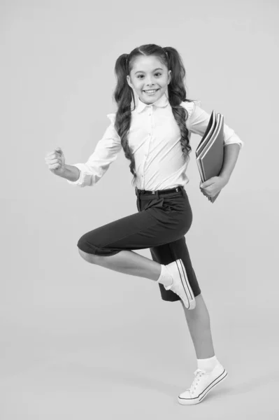 Uma literatura inspiradora. Menina adorável correndo com livros de literatura inglesa sobre fundo amarelo. Bonito criança pequena gosta de ler literatura infantil. Preparação para um exame de literatura — Fotografia de Stock