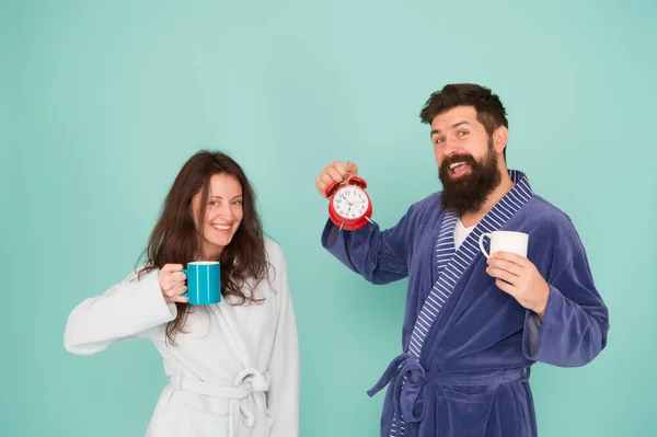 Rutina de vida familiar. pareja en el reloj despertador del amor. relaciones amorosas. hora del té en casa. Mañana dura. pareja bebe café. hombre barba y chica taza de café. Hora de despertarse. lleno de energía. energía y cansancio — Foto de Stock