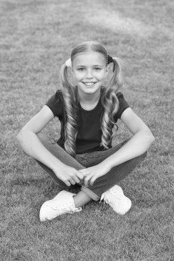 Küçük tatlı kız at kuyruğu saç stili yeşil çimlerde dinlenme, yaz tatili konsepti.