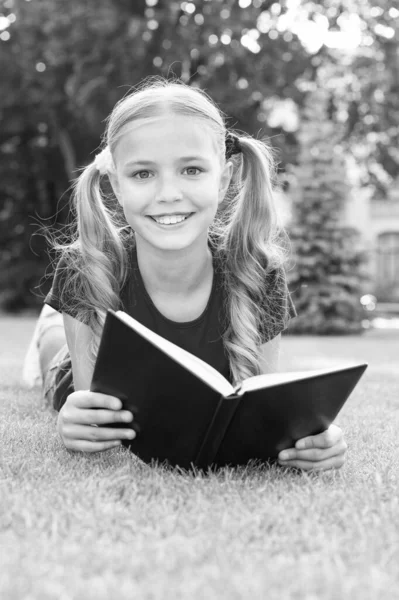 Menina pequena penteado bonito leitura livro relaxante natureza fundo, conceito de estudante inteligente — Fotografia de Stock