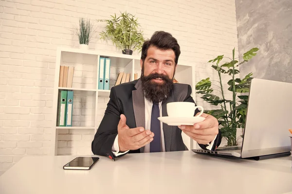 Rutinas de vida de oficina. Buenos días. Discuta los negocios con café. Un director respetable. Un jefe guapo se sienta en la oficina bebiendo café. Cómodo espacio de trabajo. Traje formal hipster barbudo relajándose con café — Foto de Stock