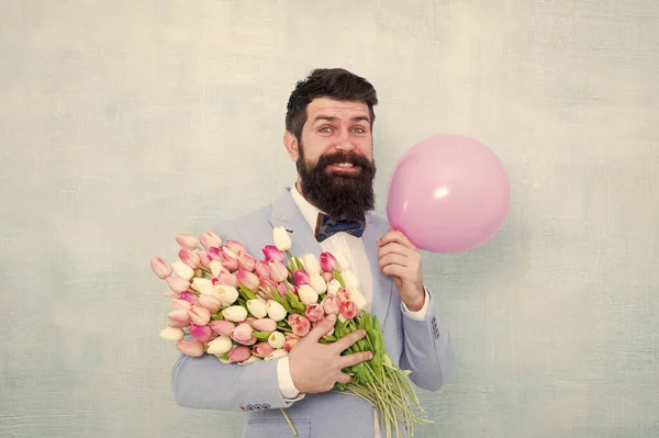 Fête d'anniversaire. Homme barbu hipster avec bouquet de fleurs. 8 mars. Fleurs pour la journée des femmes. Homme barbu avec des tulipes. Humeur printanière. Un rendez-vous amoureux. Bouquet cadeau. Présent pour le conjoint. Homme avec ballon à air — Photo