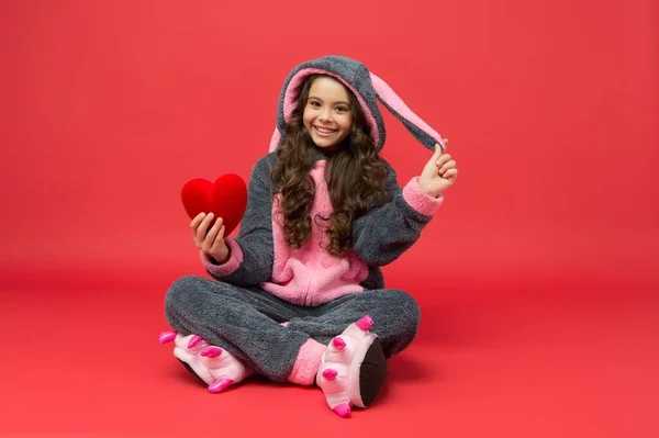 Terapia e amor. Criança feliz em pijama de coelho segurar coração vermelho. Diagnóstico cardiológico. Cardiocirurgia — Fotografia de Stock