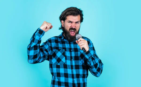 Hipster com cabelos longos e bigode cantar música. Homem em karaoke. música e conceito vocal. Homem barbudo de camisa quadriculada com microfone. cara casual cantor de música country — Fotografia de Stock