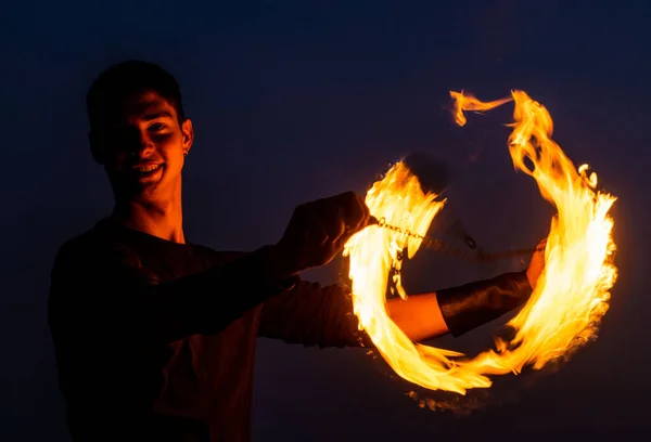 Game of light and dark. Fire spinner at night. Happy male spinner spin burning poi. — Stock Photo, Image