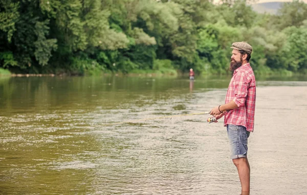 Diversão de pesca é pegar. Fisher com equipamento de pesca. Peixe no anzol. Homem brutal usar botas de borracha ficar na água do rio. Atividade de fim de semana Fisher. Lazer na natureza selvagem. Pesca hobby masculino — Fotografia de Stock