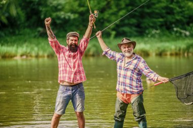 Yaz tatili. Mutlu neşeli insanlar. Elinde olta olan balıkçı. Aktivite ve hobi. Tatlı su gölü göleti nehrinde balık tutuyorum. Sakallı adamlar balık yakalıyor. Usta yemleyici. Olgun bir adam ve arkadaşı balık tutuyor.