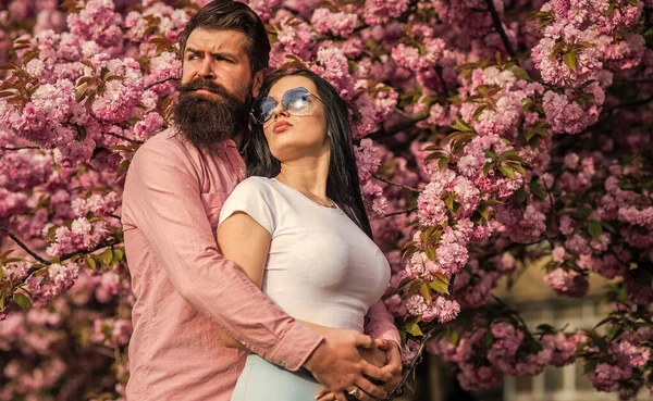 Couple relaxing in garden. Spring inspiration. Our place of power. Positive vibes. Fashion people. Spring collection. Bearded hipster hug pretty girl. Travel together. Ideas for spring vacation
