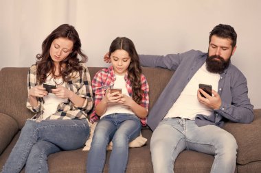 Çevrimiçi aile. Aile hafta sonunu internette geçiriyor. Küçük bir kız çocuğu, ailesine karşı akıllı telefon kullanıyor. İnternette aile sörfü. Anne baba ve kızı kanepede dinleniyor. Aile eğlencesi. Oyun uygulamasını çal