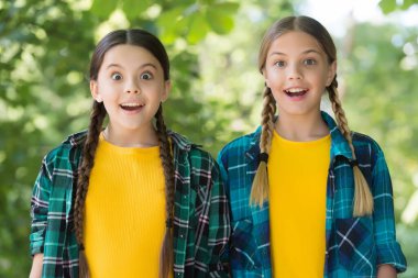 Şaşırmış küçük kızlar ağızlarını ve gözlerini güzellikleriyle açık tutarlar. Sıradan moda tarzında yaz tatili, sürpriz.