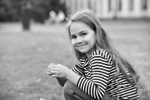 Ať se vaše dítě o něj lépe staralo. Šťastné dítě sedí venku na zadku. Děvčátko v neformálním stylu. Módní trend. Módní styl. Péče o děti a dětství. Mezinárodní dětský den — Stock fotografie