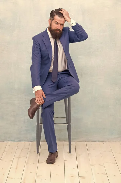 Уверенный и стильный. Классный хипстер сидит на стуле. Бородатый мужчина трогает хипстерские волосы. Модный хипстерский стиль. Парикмахерская моды. Деловой дресс-код и официальная одежда. Хипстерский образ жизни — стоковое фото