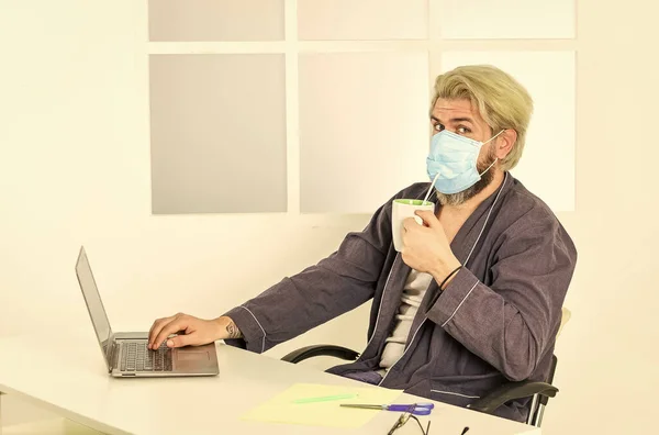 Trabalho remoto. Trabalhador com máscara médica. Tudo que você precisa para o dia produtivo. Totalmente protegido. Escritório. Usar máscara protege do coronavírus. Homem mascarado bebe café com palha. Saneamento grave — Fotografia de Stock