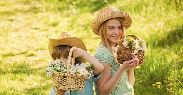 Fleurs sauvages dans les champs. Joyeuses fêtes. Mère et mignon fils portent des chapeaux de paille. Ferme familiale. Belle famille en plein air fond de nature. Famille Cowboy ramassant des fleurs dans des paniers. Concept de ranch — Photo