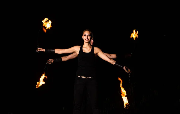 Happy couple of fire performers spin burning pois at night dark outdoors, action