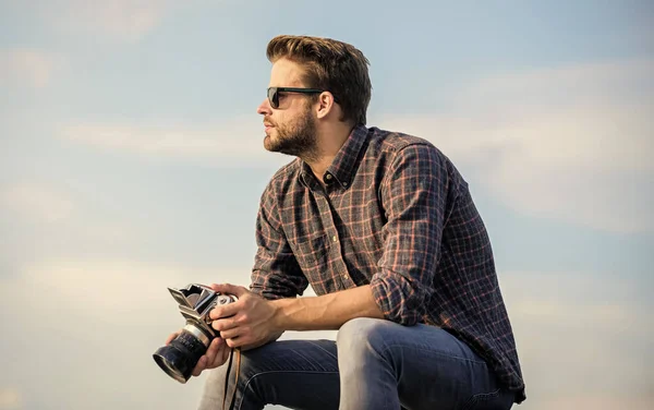 Le gars à l'extérieur fond bleu ciel. Du matériel vintage. Le journaliste prend une photo. Photographe hippie. Un blogueur qui tire sur Vlog. Beau blogueur gars voyageur caméra rétro. Réglages manuels. Blogueur de voyage — Photo