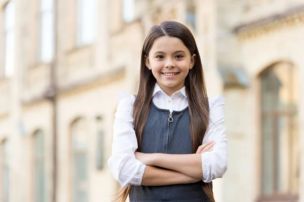 Αυτοπεποίθηση χαρούμενο παιδί χαμόγελο σε σχολική στολή κρατώντας τα χέρια σταυρωμένα σε εξωτερικούς χώρους, εμπιστοσύνη — Φωτογραφία Αρχείου