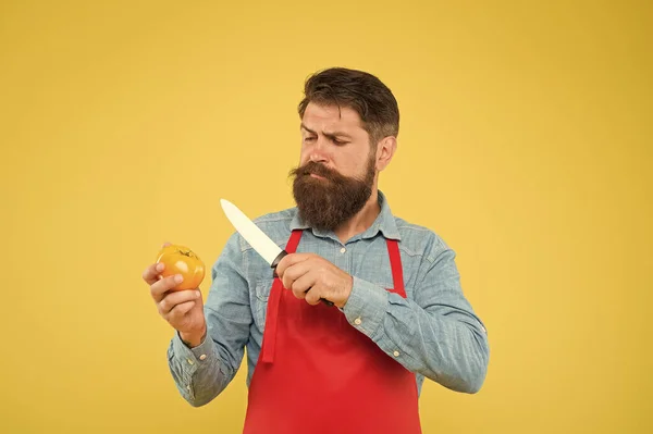 Sweet and soft. cooking healthy and fresh food. Handsome male chef is working. mature cook cut vegetable. guy in uniform on kitchen. vitamin dieting. bearded man in red apron with yellow tomato — Stock Photo, Image