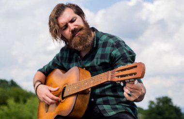 Yakışıklı sakallı, şık saçlı, akustik gitar çalan, şarkıcı.