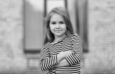 Özgüven içten gelir. Kendine güvenen bebek şehir dışında kollarını kavuşturuyor. Moda çocuğuna özgüvenli bir bakış. Modayı takip eden çocuklar giyer. Çocuk kıyafetleri. Sıradan moda trendi. Kendinden emin ve güzel.