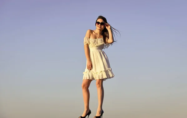 Mooi vrouwtje. mooie jonge mooie vrouw met een zonnebril. Zomer outfit. Portret van het mooie meisje. strand mode stijl. Zomer buiten levensstijl. gelukkig jong vrouw poseren over blauwe hemel — Stockfoto