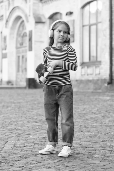 Skateboarding είναι επίσης μεταφορά. Ένα μικρό παιδί κρατάει το ταμπλό έξω. Οδός και πάρκο skateboarding. Αθλητική δραστηριότητα. Ελεύθερος χρόνος και ελεύθερος χρόνος. Ενεργό χόμπι. Ταξίδι περιπέτειας. Καλοκαιρινές διακοπές — Φωτογραφία Αρχείου