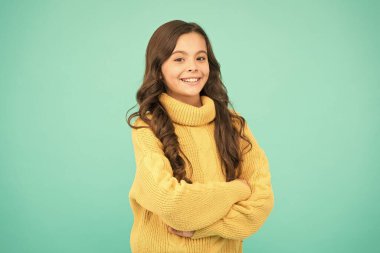 Moda çocuğu için moda tasarımı. Küçük kızın saf güzelliği. Çocuk sıradan kış modası tarzında. Çocuklar için örgü örüyorum. Mavi arka planda küçük bir kız. Uzun esmer saçlı küçük bir kız.