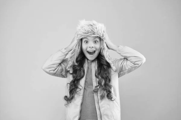 Enfant ludique fille porter un chapeau de fourrure avec des rabats d'oreille fond rose. Accessoire en fourrure souple. Chapeau enfant à poils longs en fourrure douce profiter de douceur. Concept de mode d'hiver. Chapeau chaud par temps froid. Fausse fourrure tendance — Photo