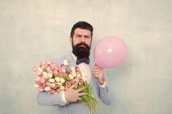 Geschenk für den Ehepartner. Mann mit Luftballon. Geburtstagsfeier. Bartträger Hipster mit Blumenstrauß. 8. März. Blumen für den Frauentag. Bärtiger Mann mit Tulpen. Frühlingsstimmung. Liebesdatum. Geschenkstrauß — Stockfoto