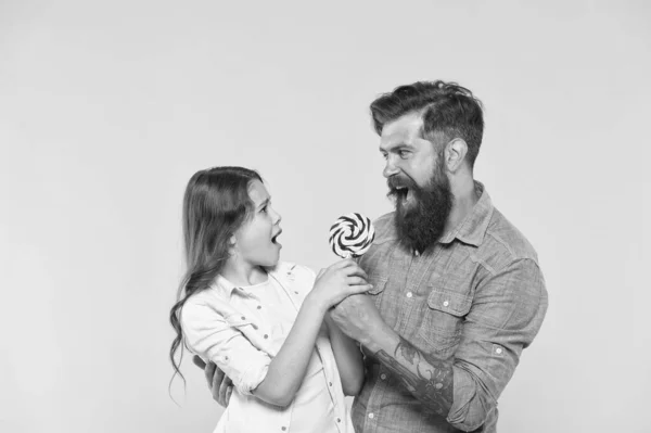 Boldog család apa és lánya enni nyalóka sárga háttér, vicces csata koncepció — Stock Fotó